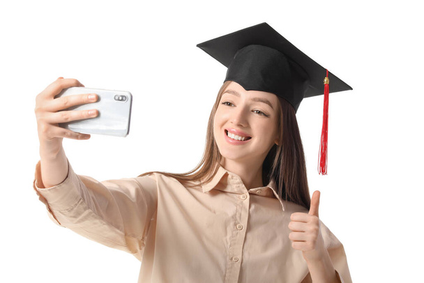 Happy female graduating student taking selfie on white background - Photo, image