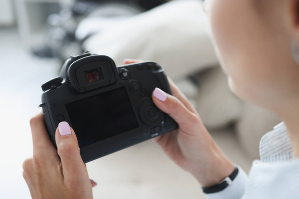 Woman holding black professional camera in her hands closeup - Zdjęcie, obraz