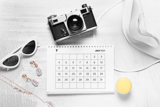 Calendario, cámara fotográfica y accesorios femeninos sobre fondo claro - Foto, Imagen