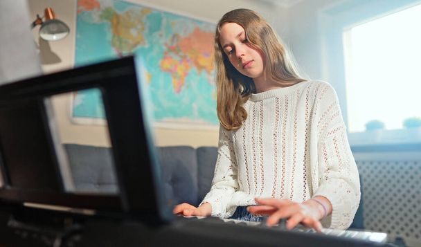 Teenager-Mädchen spielt zu Hause elektronisches Musikinstrument. - Foto, Bild