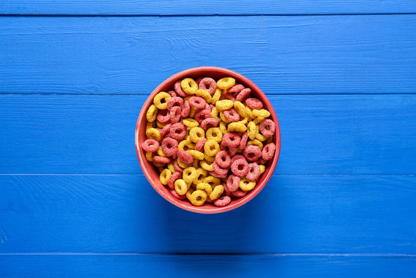 Bowl with cereal rings on color wooden background - Photo, Image