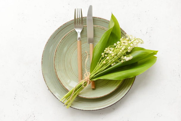 Beautiful table setting with lily-of-the-valley flowers on light background - Fotó, kép