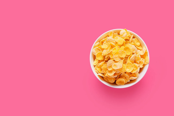 Schüssel mit leckeren Cornflakes auf farbigem Hintergrund - Foto, Bild