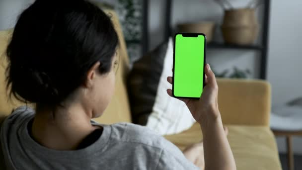 A Woman's Hand Holds A Smartphone With A Green Screen For Chromakey, Watches Social Networks, Movies, Videos, Lies on The Sofa in A Cozy Room - Filmati, video