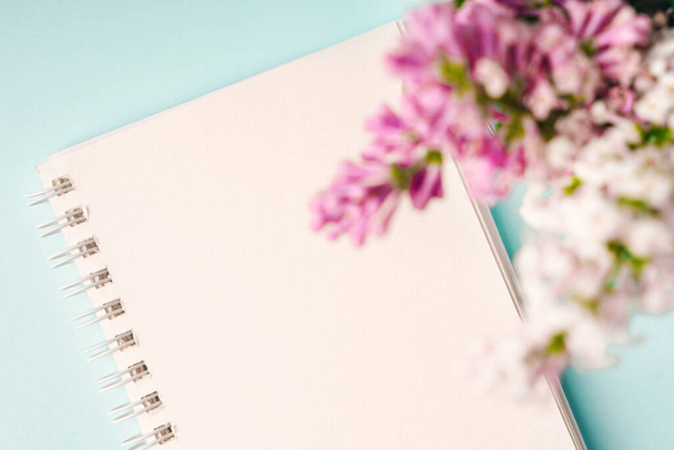 A workspace with note paper and a lilac floral composition. Beautiful spring background with space for text, top view - Foto, imagen
