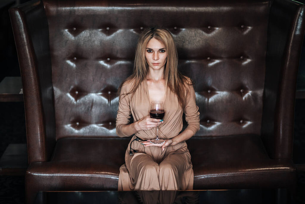 Een vrouw houdt een glas rode wijn vast in een restaurant. - Foto, afbeelding