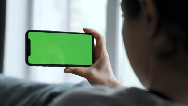 A Woman's Hand Holds A Smartphone With A Green Screen For Chromakey, Watches Social Networks, Movies, Videos, Lies on The Sofa in A Cozy Room - Video, Çekim