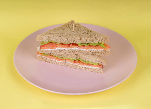 Comida, café da manhã, manhã e almoço conceito. Sanduíche de pão de centeio saudável fresco com presunto, alface e tomate seco no moderno fundo amarelo. Espaço de cópia - Foto, Imagem