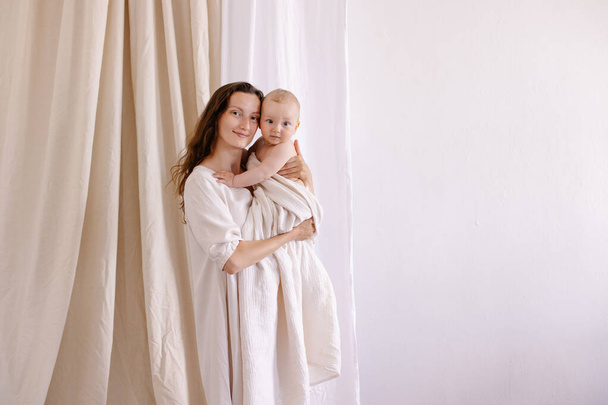 mother in white clothes kiss a baby. Purity innocence sanctity of motherhood. Mom and child. happiness of motherhood. Eco parenting vegan. Closeness to nature. Happy childhood care. Natural fabric - Photo, image