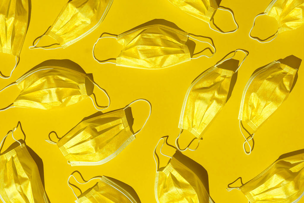 pattern with many golden medical masks isolated on a bright yellow background. hard shadows from the sun at noon - Photo, image