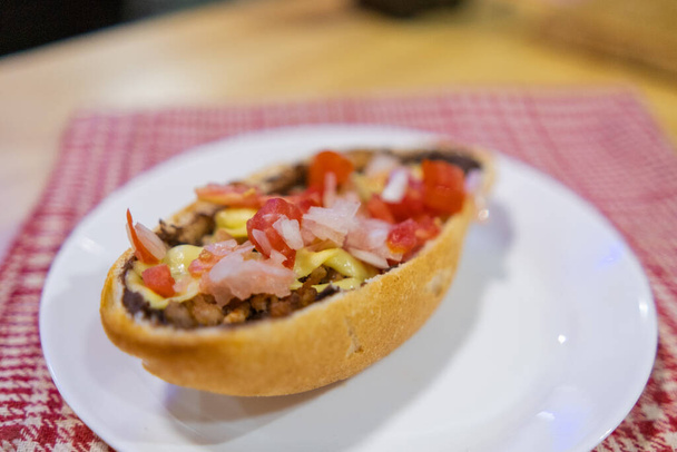 Tradiční mexický mollete na talíři nad bílým a červeným kostkovaným ubrouskem - Fotografie, Obrázek