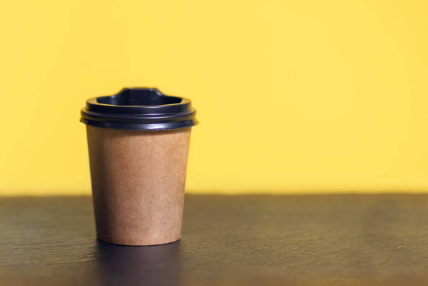Tasse à café jetable pour café sur une table de bar. Modèle en carton marron de tasse à café écologique avec place pour le texte. Modèle de boissons chaudes jetables en plastique et en papier - Photo, image