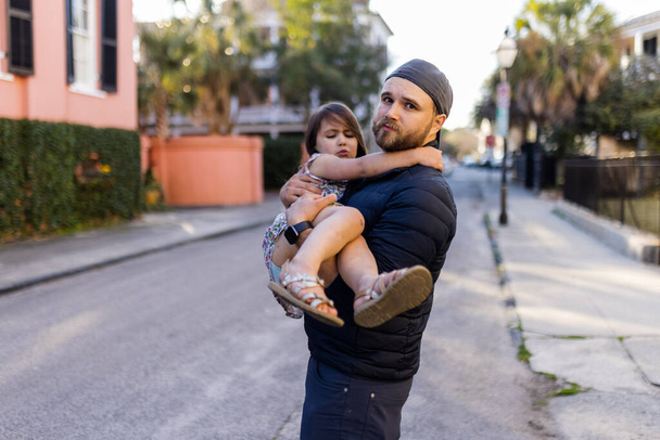 Barbuto padre portando la sua piccola figlia carina in strada sfocata - Foto, immagini