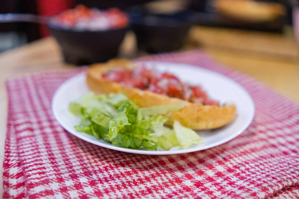 Мексиканский моллет и салат на тарелке над белой и красной клетчатой салфеткой - Фото, изображение