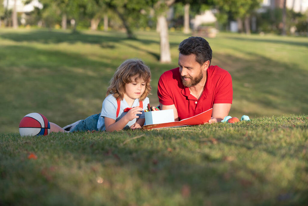 padre e hijo dibujando al aire libre. feliz día de los padres. familia feliz. papá y niño niño relajarse en la hierba - Foto, imagen