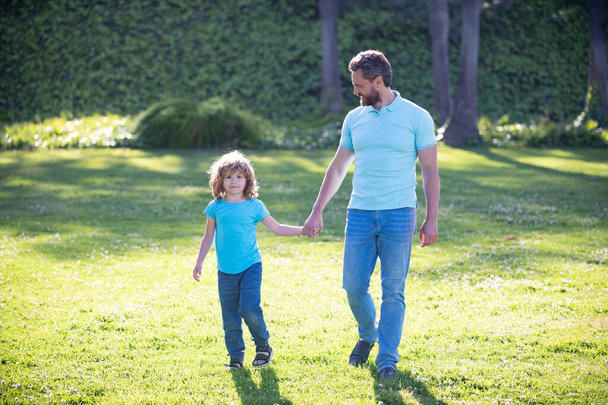 happy family value. childhood and parenthood. parent leads little child boy on grass. - Photo, Image