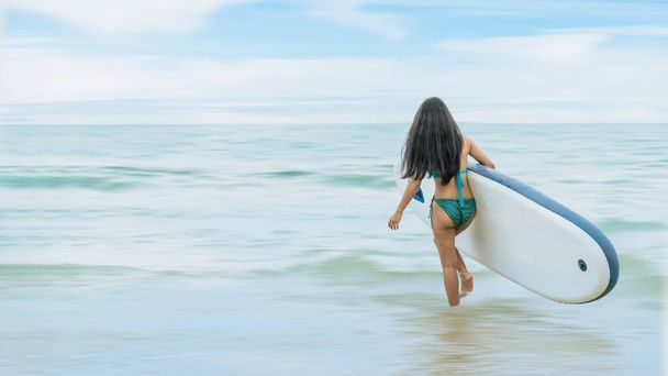 pretty woman surfer in bikini with surfboard walking  to sea for surfing during summer vacation. concept of summer leisure activity on beach - Zdjęcie, obraz