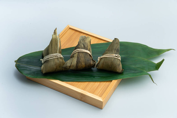 Drie zongzi 's op een bamboe dienblad. Drie rijstknoedels op een bamboe dienblad - Foto, afbeelding