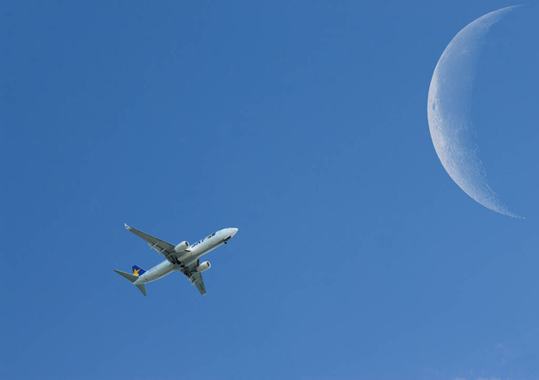 avión en medio del cielo azul con una luna en el fondo - Foto, Imagen