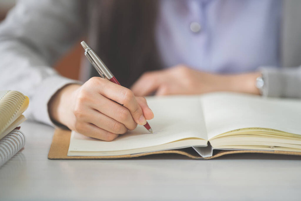 Stockfoto van een jonge tiener vrouw Aziatische student in studentenuniform studeren en schrijven op een notitieboek in een universitaire klas - Foto, afbeelding