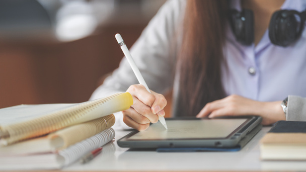 Asyalı bir üniversite öğrencisinin, üniversite sınıfında dijital tablet üzerinde çalışırken ve yazarken çekilmiş resmi. - Fotoğraf, Görsel