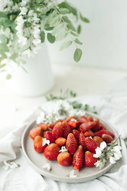 fraises fraîches sur assiette et petites fleurs blanches comme décor. nourriture saine. alimentation crue. contenu alimentaire. baies de saison. focus sélectif - Photo, image