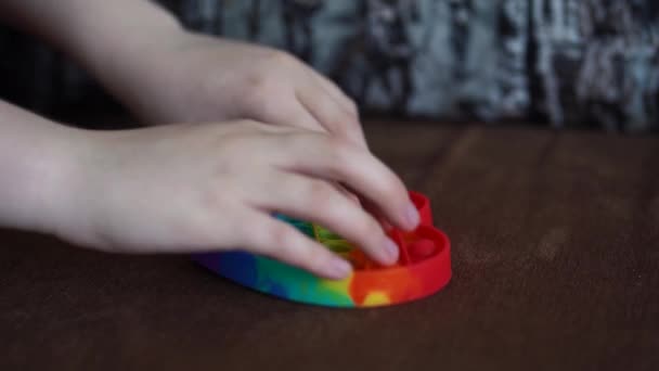 bambino che gioca con giocattolo pop esso semplice fossetta close up cuore a forma di divano - Filmati, video