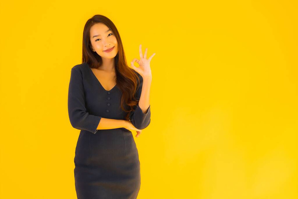 Портрет красивой молодой азиатской женщины с действием на изолированном желтом фоне
 - Фото, изображение