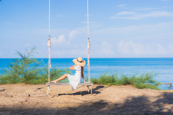 Portrait belle jeune femme asiatique se détendre sourire sur swing autour de la plage mer océan pour la nature Voyage en vacances - Photo, image