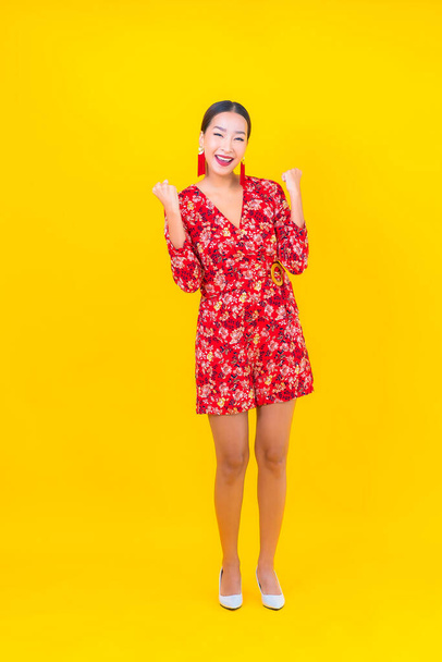 Ritratto bella giovane donna asiatica sorriso in azione in cinese nuovo concetto anno su sfondo colore - Foto, immagini