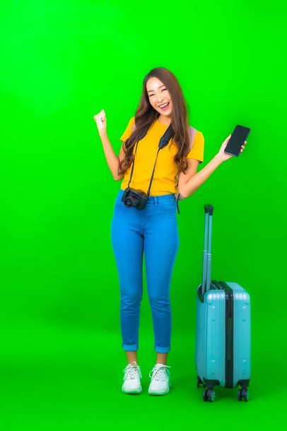 Portret pięknej młodej azjatyckiej kobiety z aparatem fotograficznym telefon bagażu mapa gotowa do podróży na zielonym tle - Zdjęcie, obraz