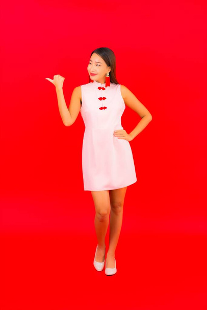 Porträt schöne junge asiatische Frau trägt chinesische Neujahrskleidung auf rotem Hintergrund - Foto, Bild