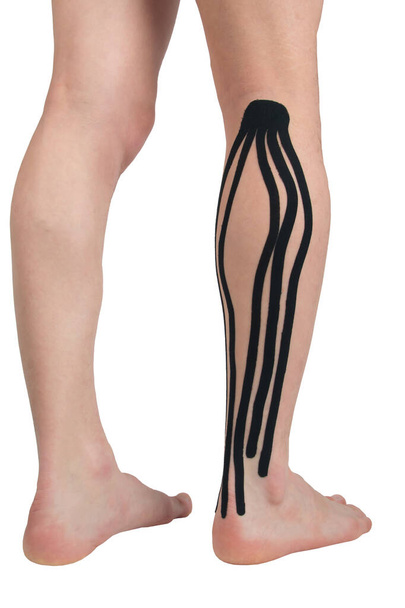 on the calf muscle of the right leg, a black kinesio tape is pasted, to relieve the load after sports and during - Foto, Bild
