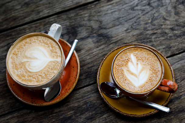 Dwie filiżanki białej kawy na drewnianym stole w kawiarni lub restauracji na świeżym powietrzu. Rustykalny styl. - Zdjęcie, obraz