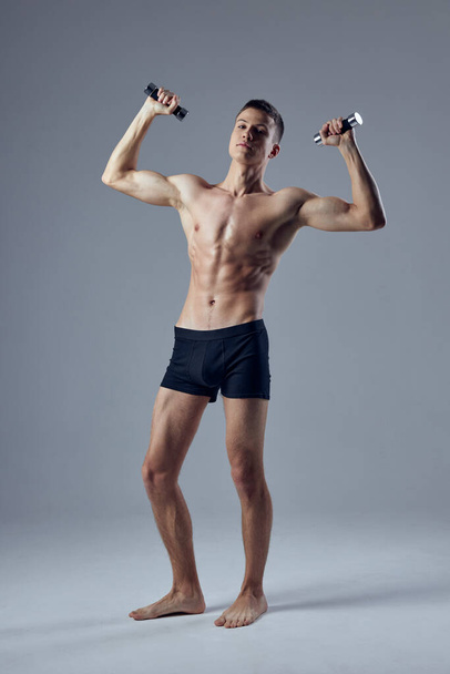 atletas do sexo masculino atlético com um corpo bombeado com halteres nas mãos  - Foto, Imagem