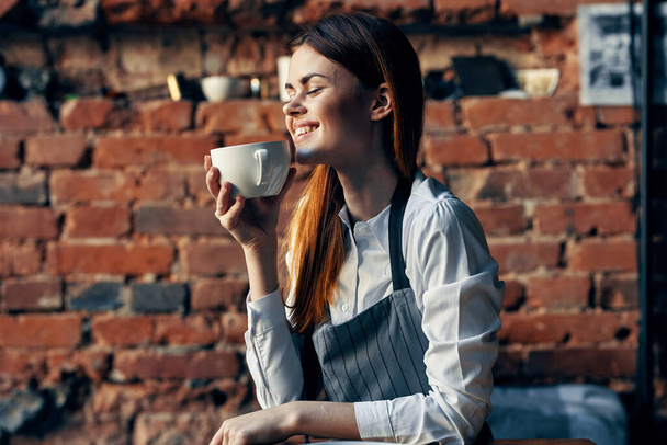 mulher garçom com xícara de café sentado à mesa  - Foto, Imagem