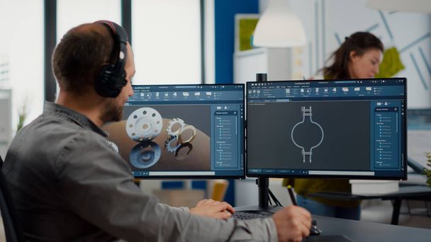 Ingeniero de diseño que se pone auriculares trabajando con el programa técnico cad - Foto, Imagen