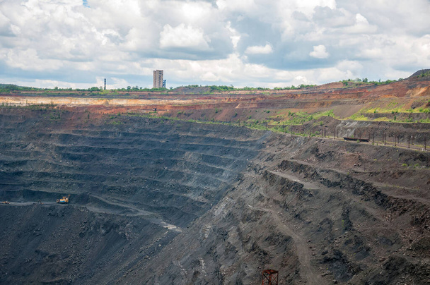 heavy dump trucks, excavators, diggers and locomotives extracting iron ore in deep quarry - Foto, imagen