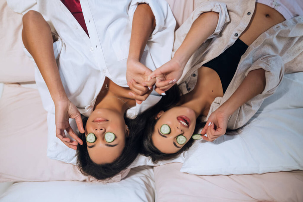 Thuis spa. Twee vrouwen met stukjes komkommer op hun gezicht - Foto, afbeelding