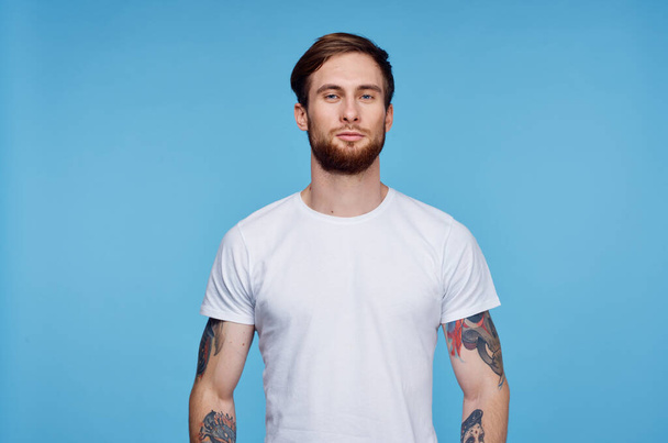 handsome man in white t-shirt tattoos on his arms cropped view blue background - Fotoğraf, Görsel