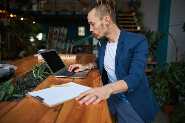 Stilvoller junger Mann mit modernem Laptop bei der Arbeit - Foto, Bild