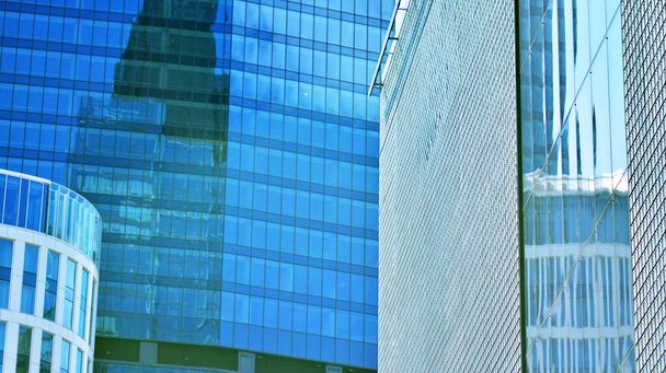 Mavi gökyüzü ve bulutlar modern ofis binasının camlarına yansıyor. Modern cam cephe.  - Fotoğraf, Görsel