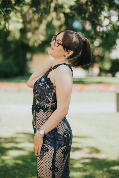 An elegant female posing in a beautiful dress in the park - Фото, изображение