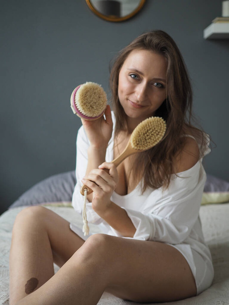 jonge vrouw doet gezicht, lichaamsmassage, anti-cellulitis massage met een droge borstel - Foto, afbeelding