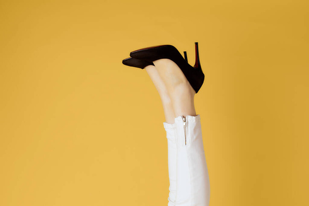 umgekehrte weibliche Beine in schwarzen Schuhen posieren gelben Hintergrund - Foto, Bild