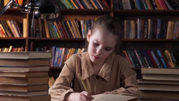 verveeld schoolmeisje kijkt in boek en schrijft in copybook - Video