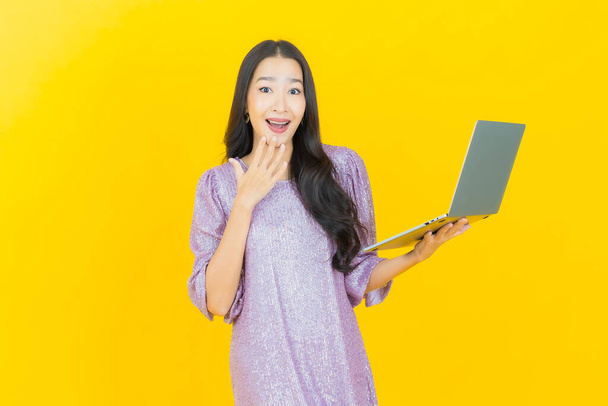 Portrait belle jeune femme asiatique sourire avec ordinateur portable sur fond isolé - Photo, image