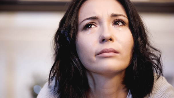κοντινό πλάνο άποψη της αναστατωμένης γυναίκας κλαίει με δάκρυα και κοιτάζοντας στο σπίτι - Φωτογραφία, εικόνα