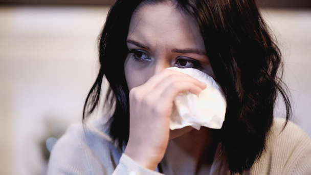 πορτρέτο της γυναίκας που κλαίει σκουπίζοντας δάκρυα με χαρτοπετσέτα στο σπίτι - Φωτογραφία, εικόνα