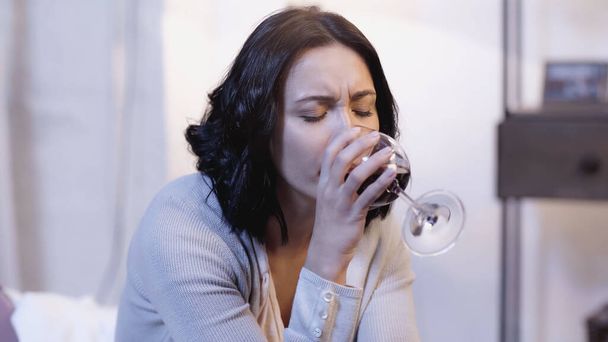 magányos nő ivás vörösbor üvegből csukott szemmel otthon - Fotó, kép